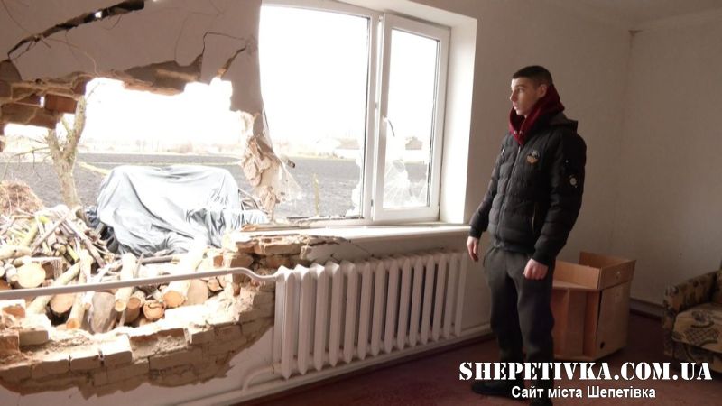 Син травмованої жінки Олег біля вибитого вікна та стіни, під якою стояло ліжко матері. 